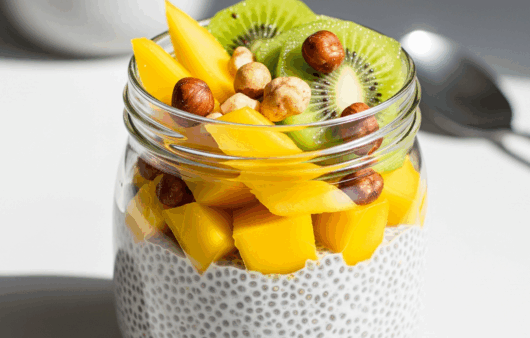 Budincă de chia cu lapte vegetal, mango, kiwi și nuci, servită într-un borcan transparent