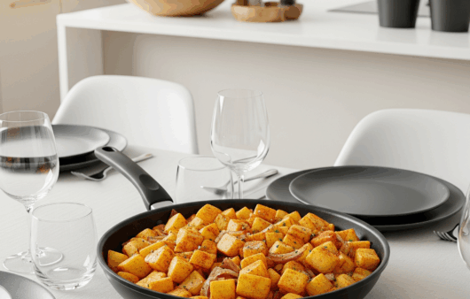 Cartofi țărănești cu ceapă caramelizată și boia dulce, serviți calzi în tigaie neagră