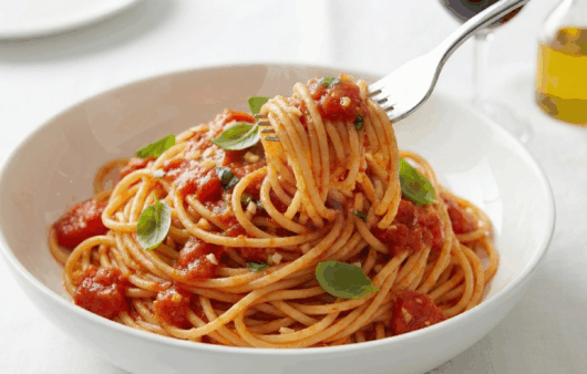 Spaghetti pomodoro servite într-o farfurie albă, sos roșu vibrant, fundal modern blurat.